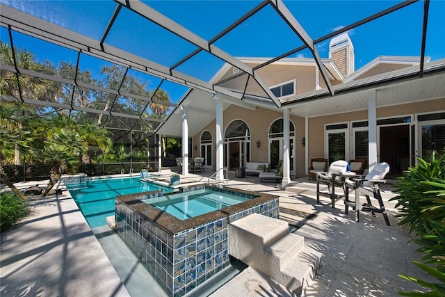 view of pool featuring an in ground hot tub, a patio, and glass enclosure