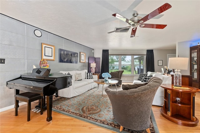 living room with a textured ceiling, hardwood / wood-style floors, tile walls, and ceiling fan