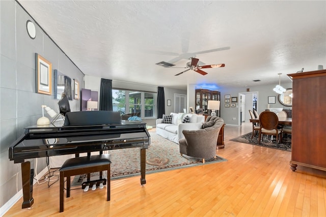 living room with wood-type flooring, ceiling fan, and a textured ceiling