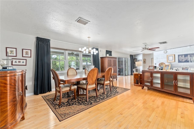 dining area featuring light wood-type flooring, a textured ceiling, and ceiling fan with notable chandelier