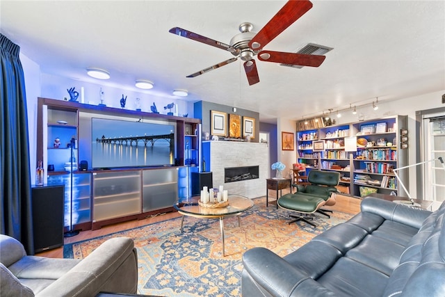 living room with a stone fireplace and ceiling fan