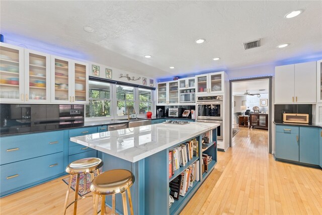 kitchen featuring white cabinets, light hardwood / wood-style flooring, stainless steel appliances, and a center island