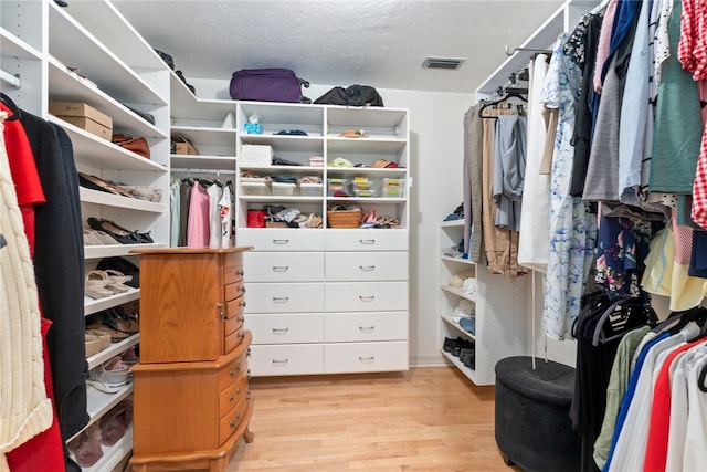 walk in closet with light hardwood / wood-style flooring