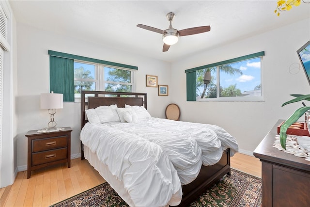 bedroom featuring multiple windows, hardwood / wood-style flooring, and ceiling fan