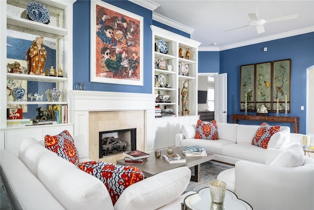 living room featuring crown molding, ceiling fan, a fireplace, and built in features