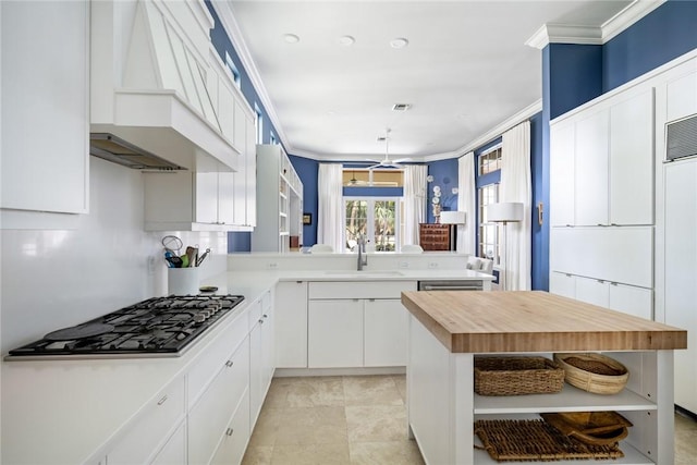 kitchen featuring stainless steel gas stovetop, sink, white cabinets, kitchen peninsula, and crown molding