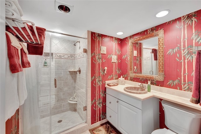 bathroom featuring vanity, a shower with shower door, and toilet