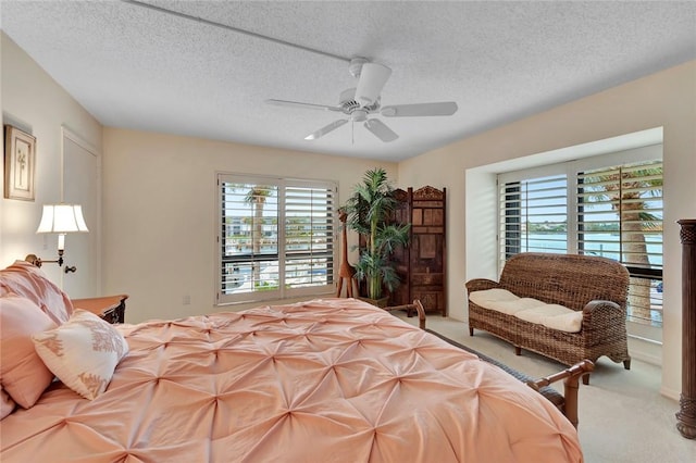 carpeted bedroom featuring ceiling fan, a textured ceiling, and multiple windows