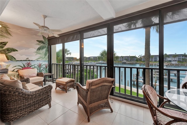 sunroom / solarium with beam ceiling, ceiling fan, and a water view