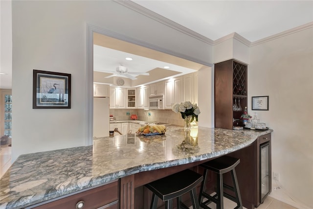 kitchen with white cabinets, white appliances, tasteful backsplash, and light stone counters