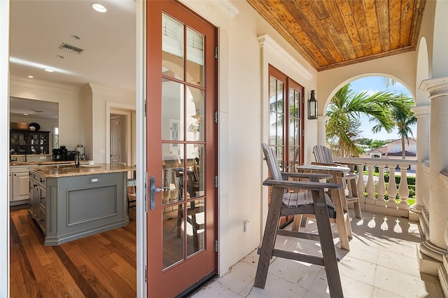 doorway with hardwood / wood-style floors, a healthy amount of sunlight, wooden ceiling, and crown molding