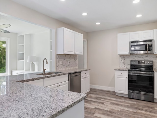 kitchen with light wood-type flooring, appliances with stainless steel finishes, sink, and white cabinets