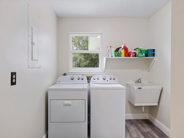 laundry room featuring washing machine and dryer, sink, and light wood-type flooring