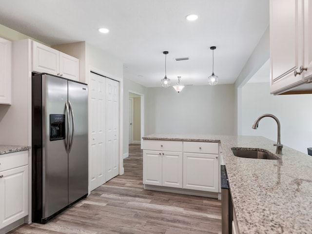 kitchen featuring stainless steel refrigerator with ice dispenser, white cabinetry, sink, and decorative light fixtures