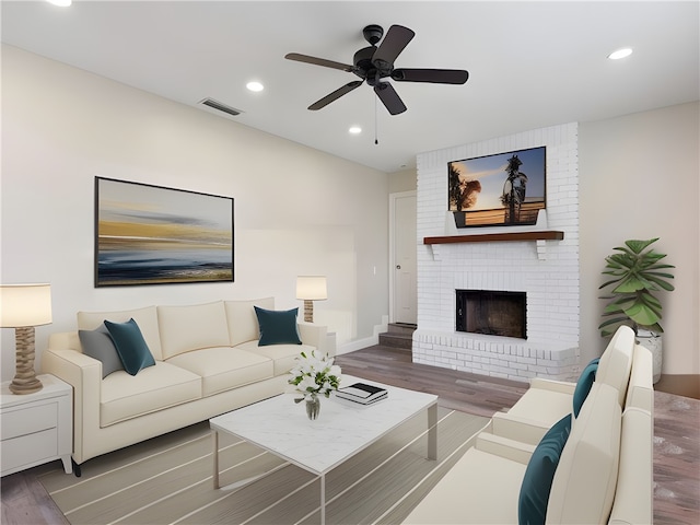 living room featuring hardwood / wood-style floors, ceiling fan, and a fireplace