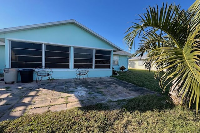 back of property featuring a patio area and a lawn