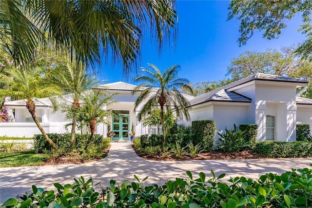 view of front of home featuring french doors, stucco siding, fence, and a tiled roof