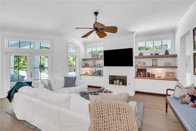 living room featuring a wealth of natural light, a glass covered fireplace, ornamental molding, and ceiling fan