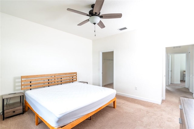 bedroom featuring light carpet, a walk in closet, a closet, and ceiling fan