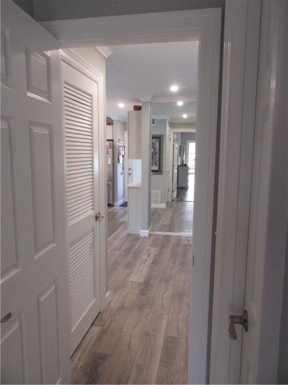 corridor featuring light wood-type flooring and ornamental molding