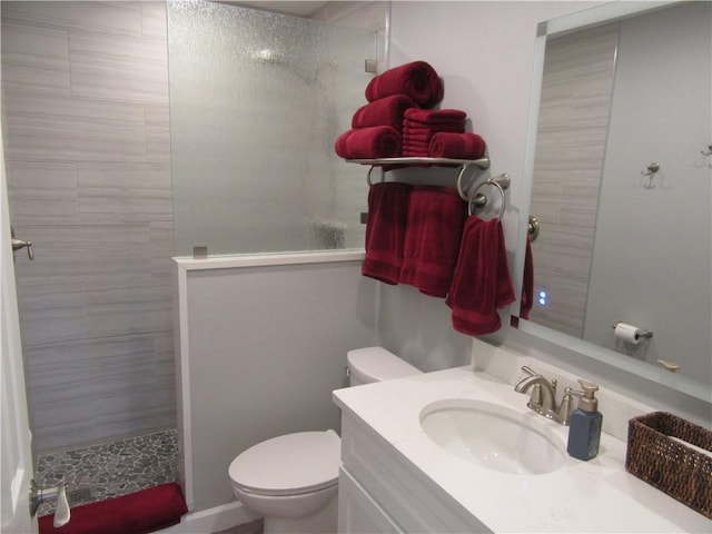 bathroom featuring vanity, toilet, and tiled shower