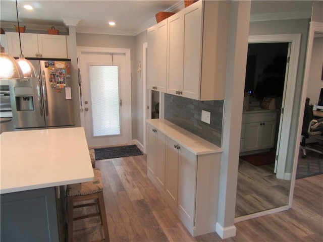 kitchen featuring white cabinets, stainless steel refrigerator with ice dispenser, backsplash, and crown molding