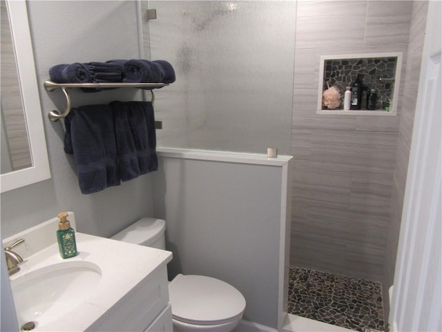 bathroom with vanity, toilet, and a tile shower