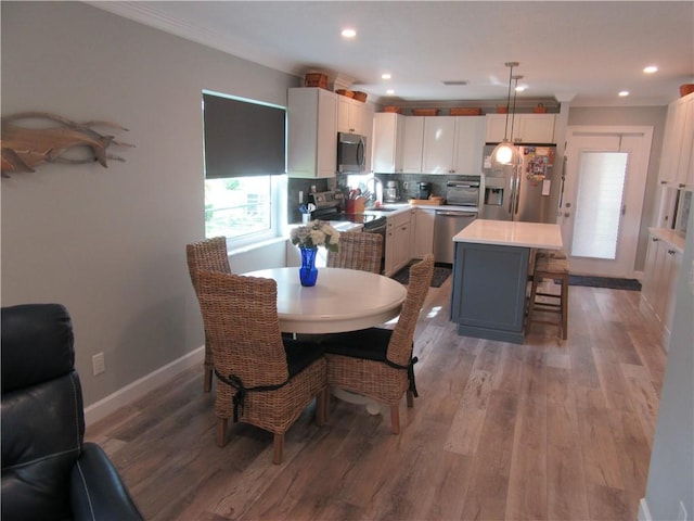 dining space featuring crown molding and light hardwood / wood-style flooring