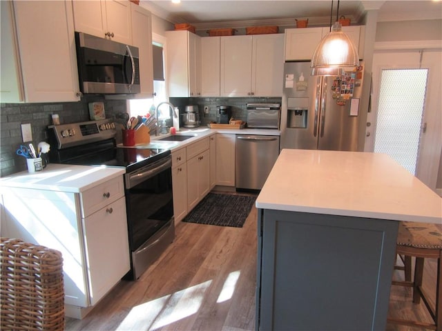 kitchen featuring white cabinets, a kitchen island, hanging light fixtures, and appliances with stainless steel finishes