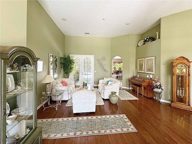 sitting room featuring arched walkways, wood finished floors, a high ceiling, and baseboards