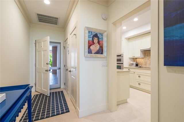 hallway featuring light tile patterned floors and crown molding