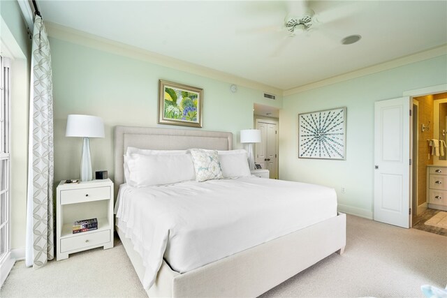 carpeted bedroom with ensuite bathroom, ceiling fan, and crown molding