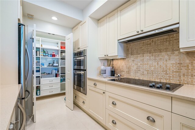 kitchen with decorative backsplash, appliances with stainless steel finishes, and light tile patterned flooring