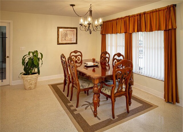 dining space featuring a chandelier, baseboards, and speckled floor