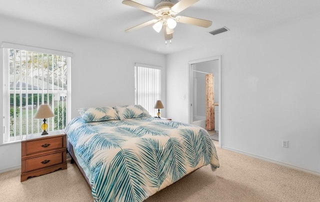 bedroom with ceiling fan, light colored carpet, and connected bathroom