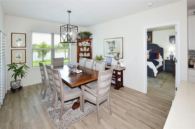 dining area with a chandelier, light wood finished floors, and a water view