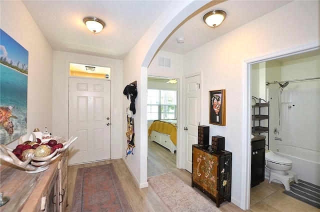 foyer featuring arched walkways and light wood finished floors