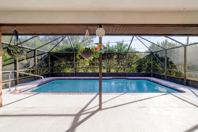 view of swimming pool featuring glass enclosure and a patio