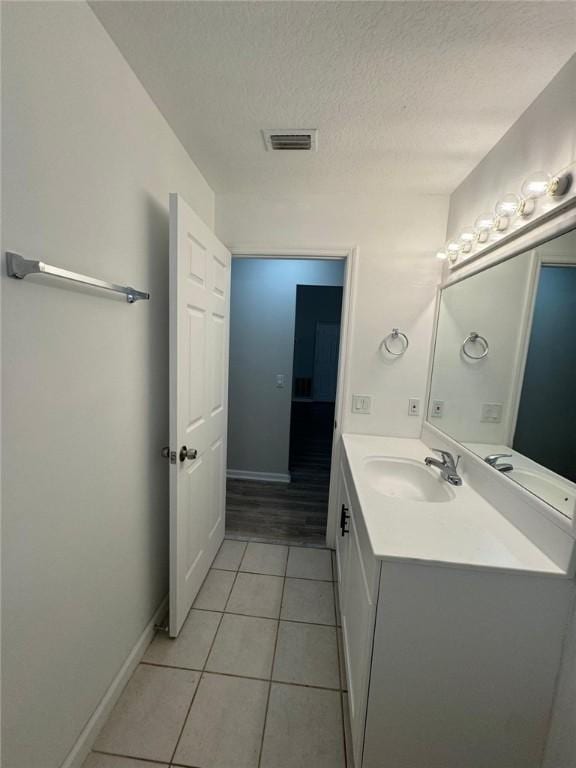 bathroom with tile patterned floors, vanity, and a textured ceiling