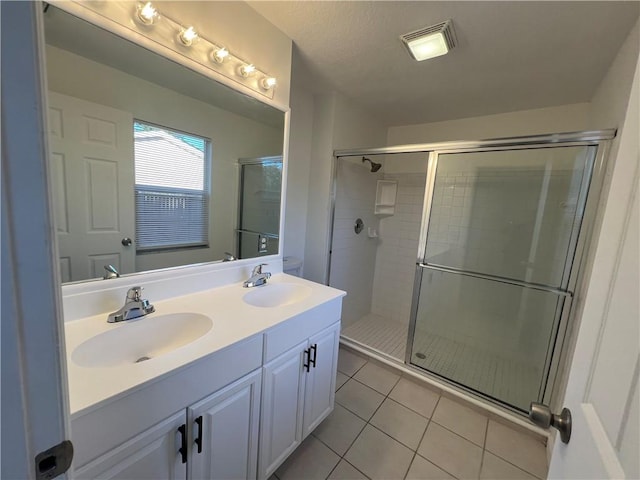 bathroom with tile patterned flooring, a textured ceiling, vanity, and walk in shower