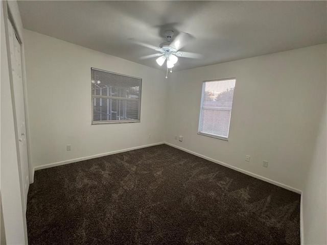 unfurnished room featuring ceiling fan and dark carpet