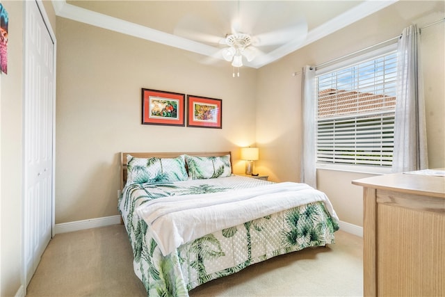 bedroom featuring ceiling fan, a closet, light colored carpet, and crown molding