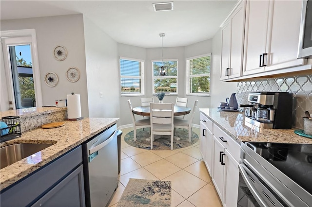 1782 Berkshire Cir SW, Vero Beach, FL 32968 - kitchen with stainless steel appliances, backsplash, light tile patterned floors, light stone counters, and hanging light fixtures