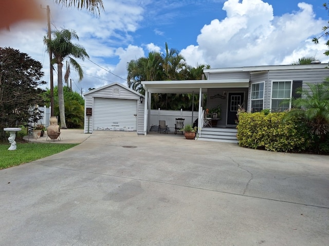 view of front facade with an outbuilding, covered porch, a garage, and driveway