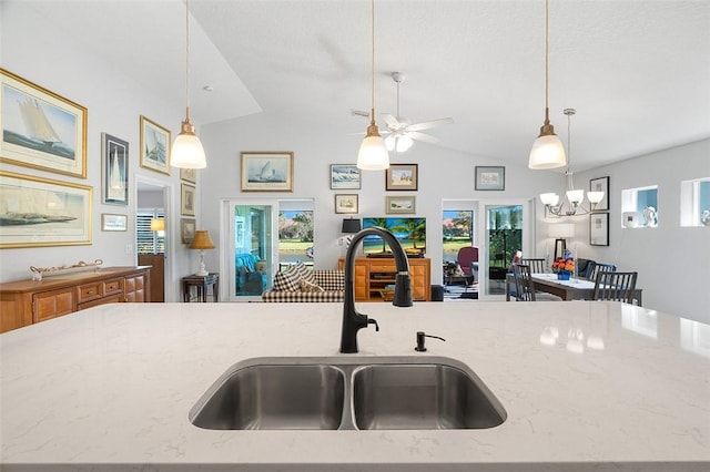 kitchen with sink, pendant lighting, lofted ceiling, and light stone countertops