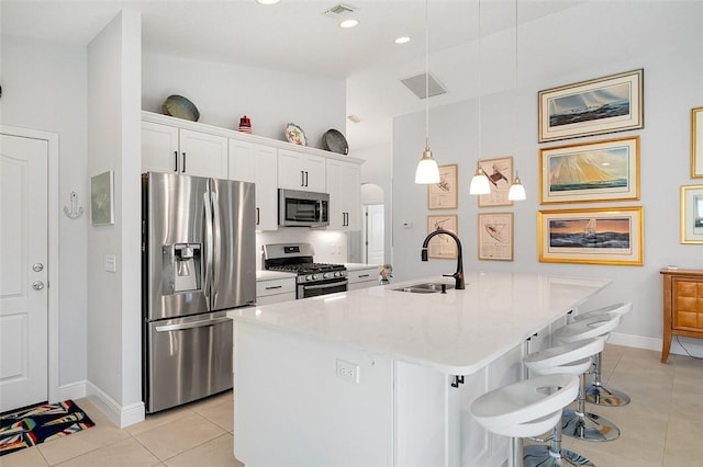 kitchen featuring sink, white cabinets, hanging light fixtures, a kitchen island with sink, and appliances with stainless steel finishes