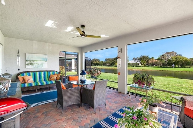 sunroom / solarium featuring ceiling fan and a water view