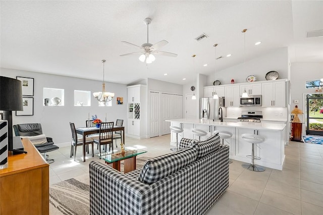 living room with ceiling fan with notable chandelier, sink, light tile patterned floors, and lofted ceiling