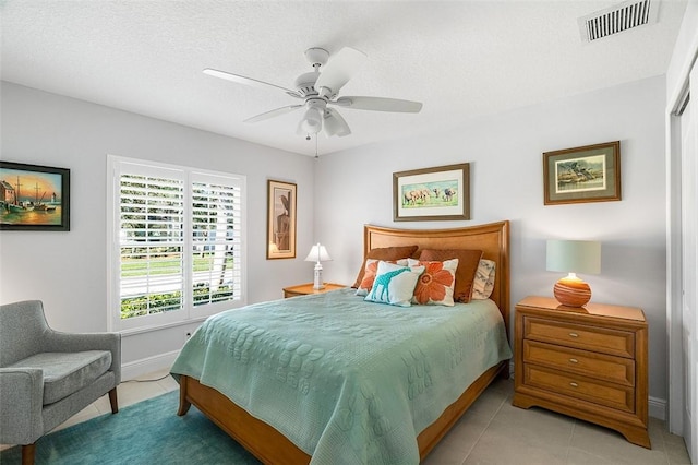 bedroom featuring a closet, light tile patterned flooring, a textured ceiling, and ceiling fan