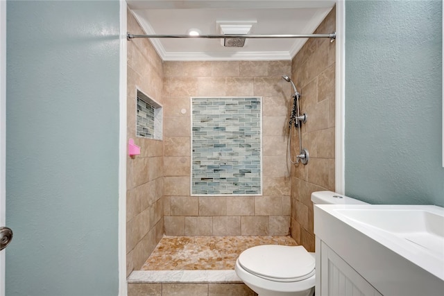 bathroom with vanity, toilet, a tile shower, and ornamental molding